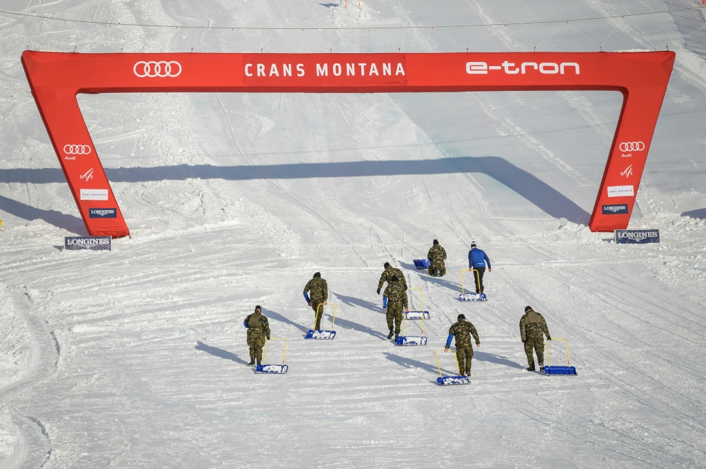 Des soldats suisses enlèvent le surplus de neige sur l'aire d'arrivée de la descente de Crans-Montana